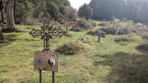Cruz de forja ornamentada con placa de madera y símbolo del yin-yang en una zona apartada del Cementerio de Sad Hill