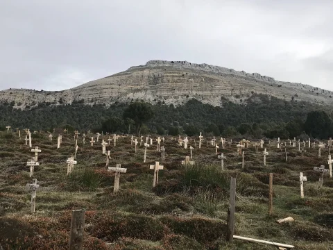 Hileras de cruces de madera en el Cementerio de Sad Hill con el relieve montañoso de fondo bajo un cielo nublado