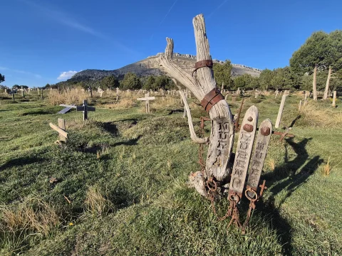 Tronco de madera con herrajes cadenas y tablas grabadas frente al mar de cruces y las Peñas de Carazo en el Cementerio