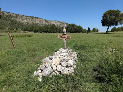 Tumba de piedras con cruz de madera rotulada Carazo 80 con la silueta de Clint Eastwood al fondo en el Cementerio de Sad Hill
