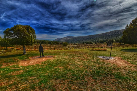 Panorámica artística del Cementerio de Sad Hill con cielo dramático, silueta de Clint Eastwood y cartel de entrada