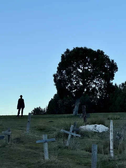 Silueta de Clint Eastwood junto a un árbol y cruces de madera en una loma del Cementerio de Sad Hill