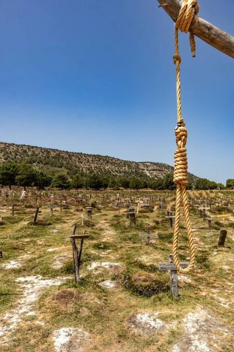Cuerda de horca colgando de una rama en primer plano frente a las cruces del Cementerio de Sad Hill