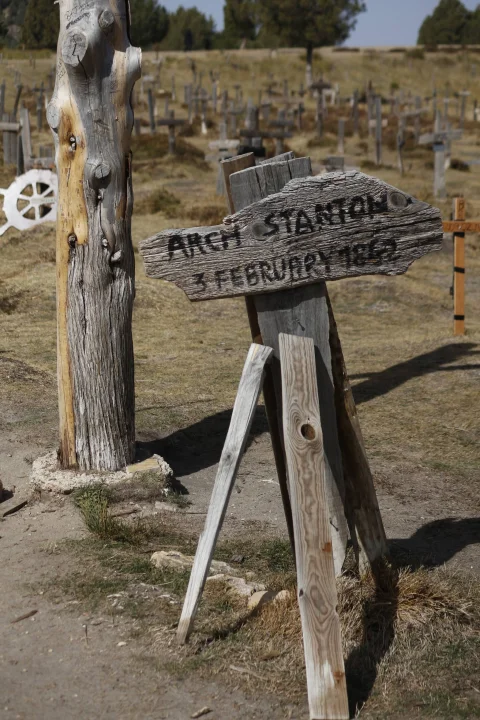 Primer plano de la tumba de Arch Stanton con fecha 3 February 1862 en madera envejecida junto al árbol central del Cementerio de Sad Hill