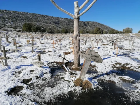 Tumbas de Arch Stanton y Unknown cubiertas de nieve con el mar de cruces invernal en el Cementerio de Sad Hill