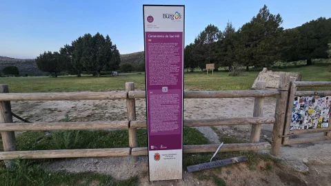 Tótem informativo morado de Burgos Origen y Destino junto a la valla de madera en el acceso y aparcamiento inferior del Cementerio de Sad Hill
