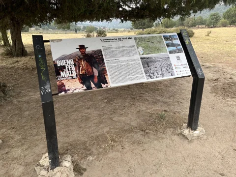 Panel interpretativo de la película El bueno, el feo y el malo bajo la sombra de los árboles en el acceso cercano al Cementerio de Sad Hill