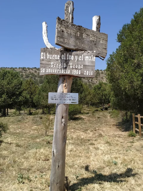 Poste de madera con carteles conmemorativos del 50 aniversario en el acceso al Cementerio de Sad Hill