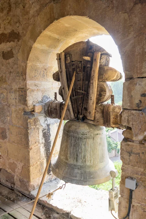 Campana de bronce con yugo tradicional de madera en el ventanal de la torre de la iglesia
