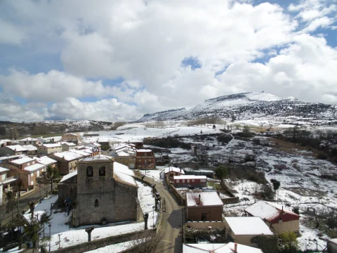 Vista aérea de Contreras nevado con la iglesia parroquial y las montañas al fondo