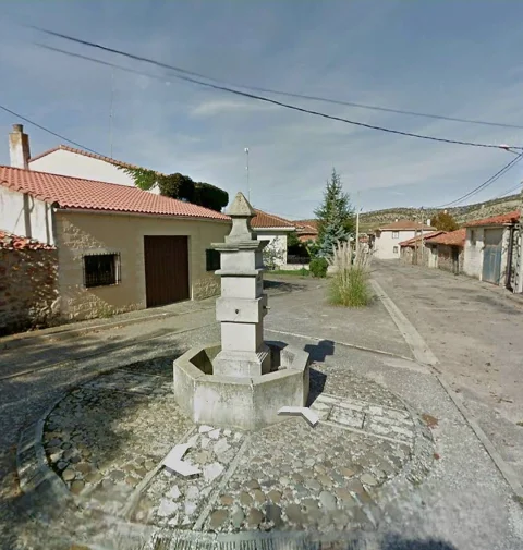 Fuente de piedra con pilón hexagonal sobre base circular empedrada en una calle de Contreras