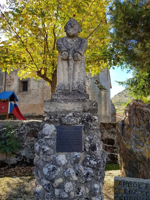 Estatua de piedra de Fernán Sasa de Contreras sobre pedestal rústico con placa conmemorativa