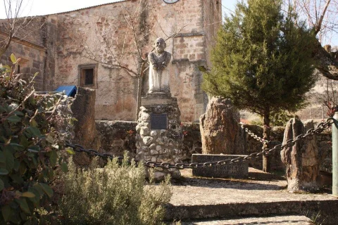 Estatua en piedra del fundador de Contreras con pedestal rústico y árboles fósiles