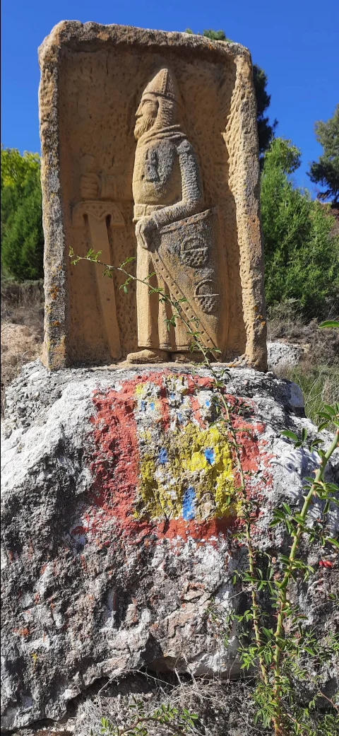 Relieve de piedra tallado con figura de caballero medieval sobre roca con escudo pintado