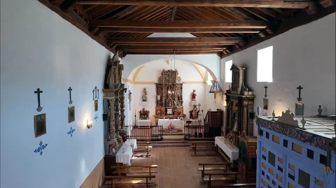 Nave interior de la iglesia parroquial con techo de vigas de madera y retablos barroco
