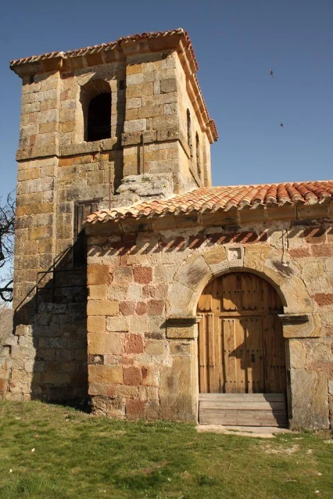 Detalle de la portada de piedra con arco y torre campanario anexa