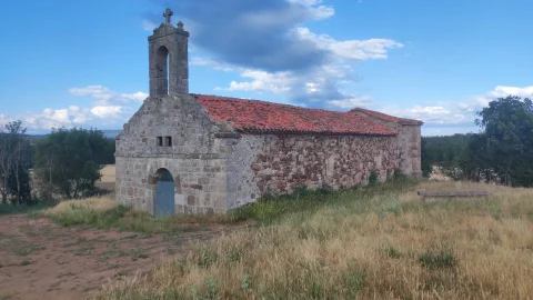 Ermita de Nuestra Señora del Amparo rodeada de campos de cereal y arbolado en La Revilla