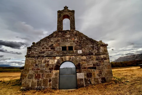 Fachada principal de piedra rústica y espadaña de la ermita de la Virgen del Amparo en La Revilla