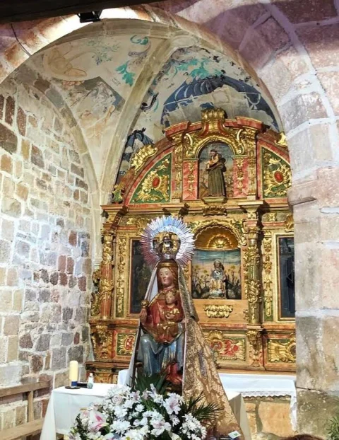 Talla de la Virgen con el Niño ante el retablo barroco en la ermita del Amparo de La Revilla