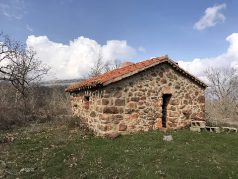 Vista en ángulo del refugio de piedra con chimenea en el entorno de La Revilla