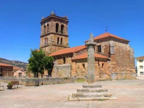 Rollo jurisdiccional de piedra en la plaza con la iglesia de San Juan Bautista al fondo en Barbadillo del Mercado