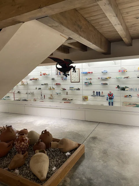 Exposición de juguetes antiguos bajo la escalera y cántaros de barro en el Museo del Juguete