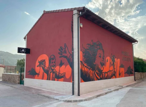 Mural exterior en esquina con ilustraciones de niños jugando en el Museo del Juguete de Barbadillo