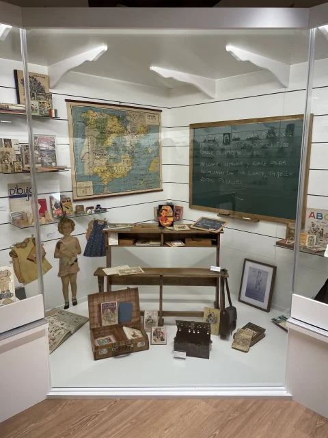 Recreación de un aula escolar antigua con pupitre, mapa y pizarra en el Museo del Juguete