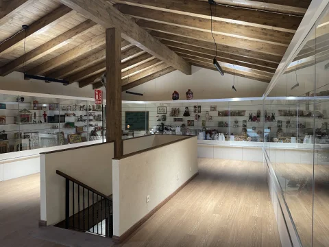 Sala abuhardillada con vigas de madera y vitrinas del Museo del Juguete en Barbadillo del Mercado