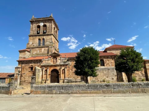Fachada principal y torre de la iglesia de San Pedro Apóstol tras el murete de piedra en Barbadillo