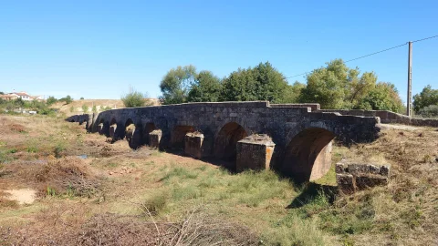 Hilera de arcos y potentes tajamares del Puente del Canto en el entorno natural de Barbadillo