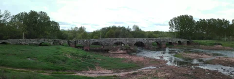 Panorámica del puente de piedra con múltiples arcos sobre el río Pedroso en Barbadillo del Mercado