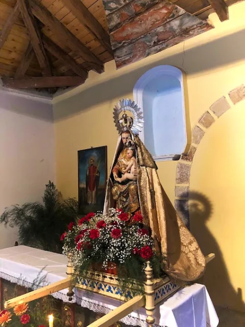 Talla de la Virgen de Villavieja con manto dorado sobre andas procesionales con flores