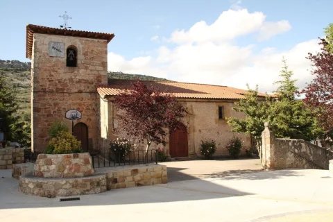 Plaza empedrada y jardinera frente a la torre con reloj de sol y nave de la iglesia parroquial de Mamolar