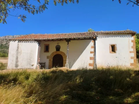 Ermita rural encalada con porche sostenido por pies derechos de madera y portada de medio punto en Mamolar