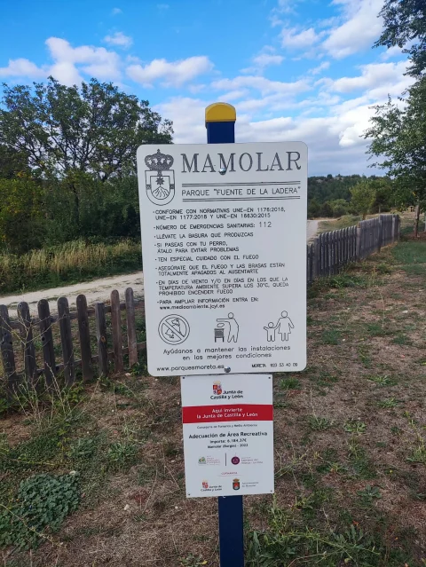 Cartel informativo blanco con el escudo de Mamolar y normas de uso del parque Fuente de la Ladera