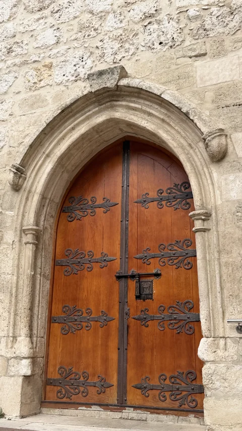 Puerta principal de madera trabajada con herrajes de hierro bajo un arco de piedra en la Iglesia de Santa Águeda