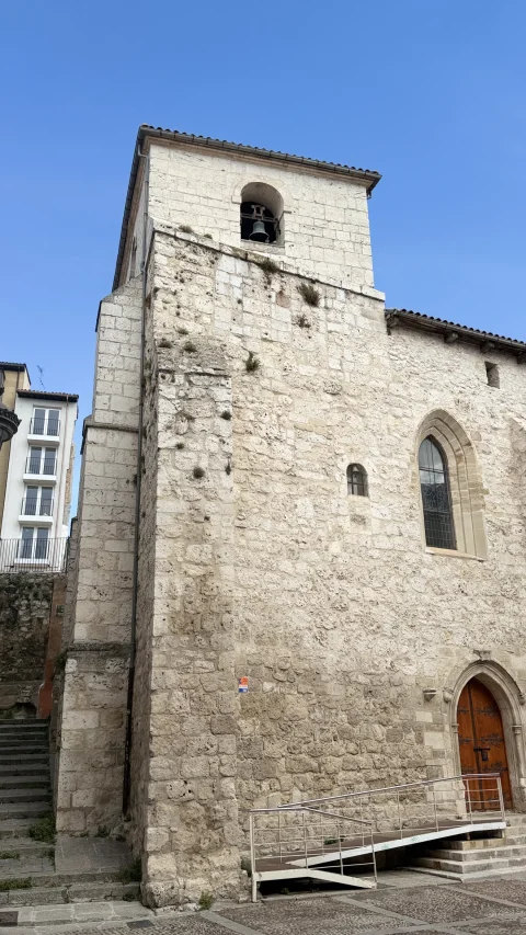 Vista lateral de la fachada de piedra de la Iglesia de Santa Águeda con su torre campanario en Burgos