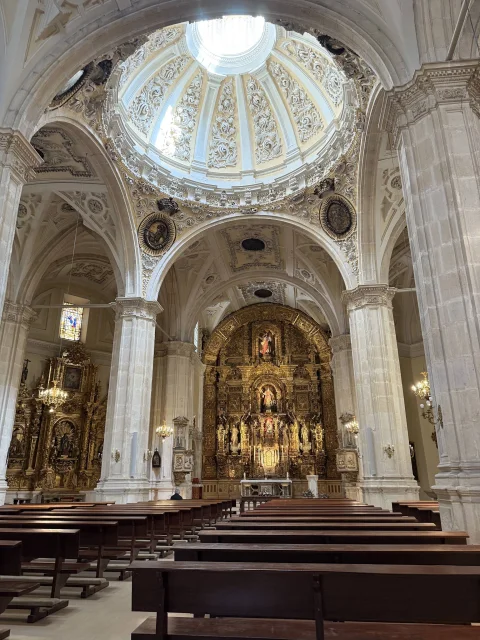 Vista del altar mayor dorado, la cúpula con linterna y la nave central con bancos de la Iglesia de San Lorenzo Real