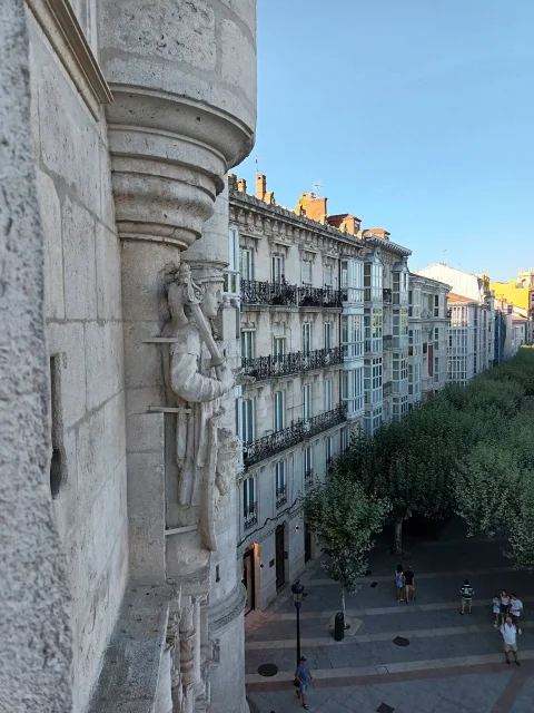 Escultura angular de macero en la torre con vista en picado sobre las galerías y peatones del Espolón