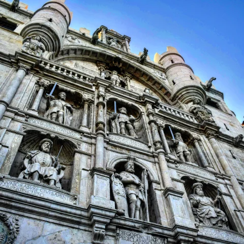 Primer plano de estatuas de piedra de héroes castellanos y el emperador Carlos V empuñando espadas en hornacinas