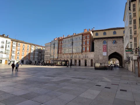 Vista amplia de la plaza empedrada con la fachada posterior de piedra del arco monumental a la derecha