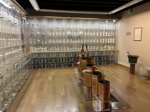 Vitrinas con albarelos y tarros de botica de cerámica junto a alambiques y recipientes de cobre