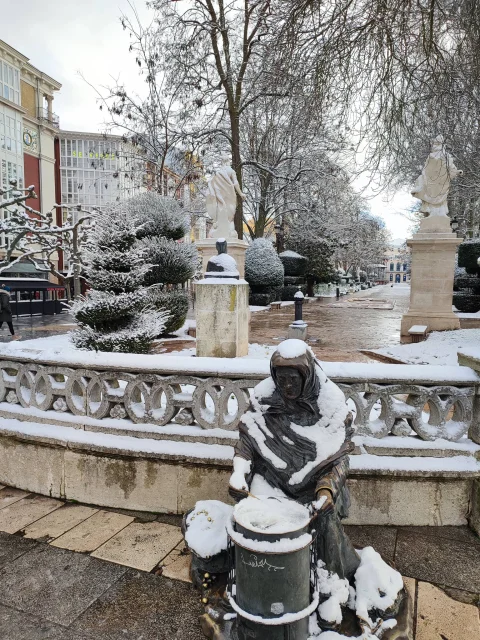 "Escultura de bronce de la castañera y árboles del paseo del Espolón cubiertos por un manto de nieve blanca
