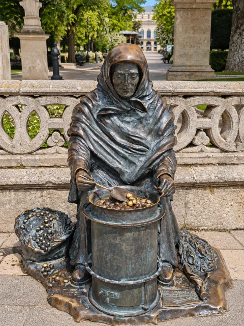 Escultura de bronce de «La Castañera» asando castañas en su hornillo tradicional