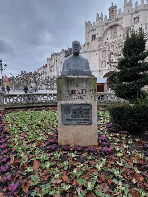 Busto de bronce de Marceliano Santa María sobre pedestal de piedra con el Arco de Santa María al fondo