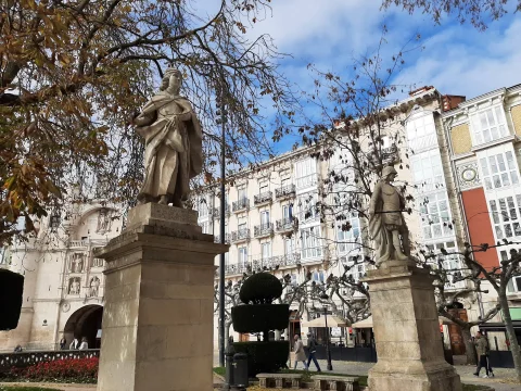 Estatuas de reyes sobre pedestales flanqueando la entrada al paseo con el Arco de Santa María detrás
