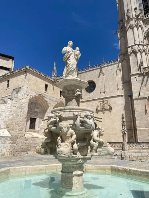 Fuente de Santa María con agua clara frente a los muros de piedra de la Catedral de Burgos