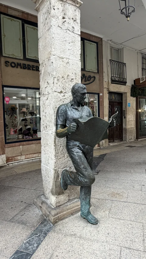 Estatua El lector de prensa en Burgos, apoyada en una columna de los soportales de la calle Sombrerería