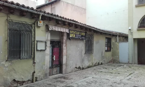 Fachada de planta baja de un antiguo restaurante con letrero de hierro